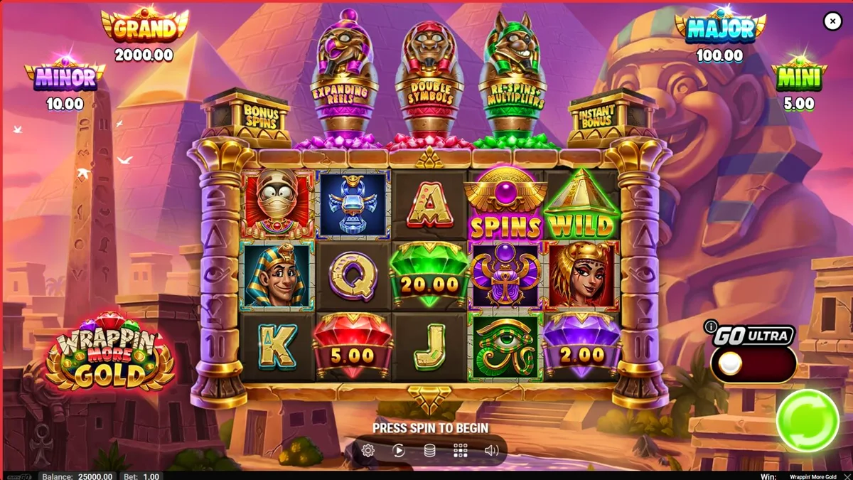 Mumi ramah dalam slot Wrappin’ More Gold dengan latar belakang harta karun Mesir